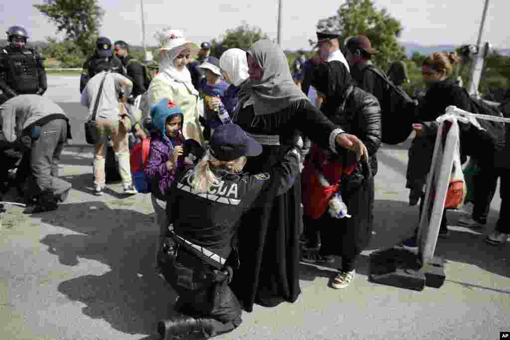 A police officer searches refugees after they entered Slovenia, as they wait for a bus transport at the border station in Obretzje.