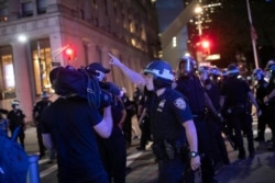 FILE - A police officer shouts at a video journalist in New York City, June 2, 2020, during demonstrations protesting the death of George Floyd.