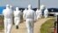 FILE - Health officials in protective suites arrive at a poultry farm where the bird flu virus was found in Jeongeup, South Korea, April 8, 2008. 