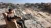 A man sits on a lounge chair atop a heavily-damaged building along Saftawi street in Jabalia in the northern Gaza Strip on Jan. 20, 2025 a day after a ceasefire deal in the war between Israel and Hamas went into effect.