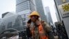 A worker uses a cell phone outside a construction site in Beijing on October 31, 2024. 