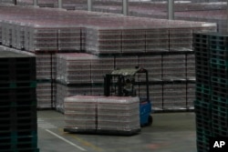 FILE - A worker transfers packages of Nongfu Spring mineral water at a factory in Danjiangkou, China, on May 11, 2023. Nongfu Spring has become a target of nationalist attacks on Chinese social media.