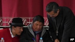 Los líderes indígenas Leonidas Iza, izquierda, y Marlon Vargas, al centro, firman un acuerdo junto a monseñor David de la Torre durante una sesión de diálogo con el gobierno en la que la Iglesia católica fungió como mediadora, el 30 de junio de 2022. 