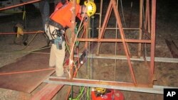 This Oct. 17, 2018, photo provided by the Maricopa County Sheriff's Office shows rescue team members lowering themselves into an abandoned mine shaft to rescue a man who had fallen into the shaft two days earlier, near Aguila, Ariz.