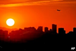 A Jet takes flight from Sky Harbor International Airport as the sun sets over downtown Phoenix, Wednesday, July 12, 2023. (AP Photo/Matt York)