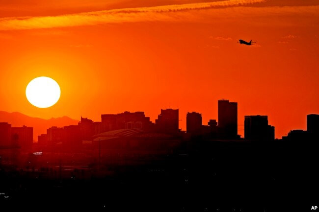 A Jet takes flight from Sky Harbor International Airport as the sun sets over downtown Phoenix, Wednesday, July 12, 2023. (AP Photo/Matt York)