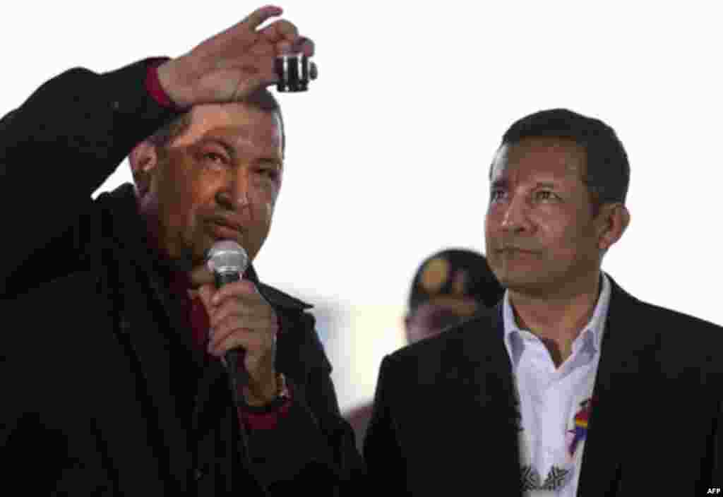 Venezuela's President Hugo Chavez, left, holds up an example of Venezuela's oil and speaks to oil workers as Peru's President Ollanta Humala watches during their visit to an oil installation in the faja petrolifera del Orinoco, or Orinoco oil belt, in the