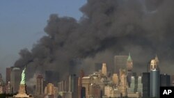 FILE - In this Sept. 11, 2001 file photo, thick smoke billows into the sky from the area behind the Statue of Liberty, lower left, where the World Trade Center towers stood. 