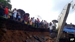 Regu penyelamat dan masyarakat sekitar berdiri di dekat tembok yang runtuh di Mumbai, India, 2 Juli 2019.