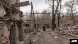 A woman walks past debris and damaged buildings after shelling in Kostyantynivka, in the eastern Donetsk region, on Feb. 7, 2025, amid the Russian invasion of Ukraine. 