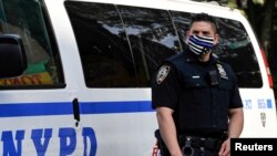 Un agente de la policía de Nueva York usa un tapabocas con líneas azules que indican su apoyo a las fuerzas del orden en la escena de un tiroteo en Brooklyn, Nueva York, e 25 de junio de 2020.