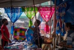 A fabric vender negotiates with a buyer at a roadside shop in Bangkok, Thailand, Aug. 5, 2020. Thailand has managed to curb COVID-19 infections over the last three months with strict controls on entry into the country.