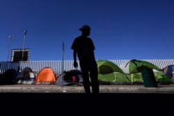 A migrant from Honduras seeking asylum in the United States stands in front of rows of tents at the border crossing, Monday, March 1, 2021, in Tijuana, Mexico. President Joe Biden is holding a virtual meeting with Mexican President Andrés Manuel…