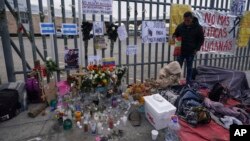 An altar with candles and photos covers the fence outside the Mexican immigration detention center that was the site of a deadly fire, as migrants wake up after spending the night on the sidewalk in Ciudad Juarez, Mexico, March 30, 2023. 