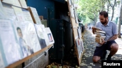 New Parisian bouquiniste, traditional street bookseller, places books on shelves along the banks of the River Seine in Paris, France, August 18, 2022. (REUTERS/Sarah Meyssonnier)
