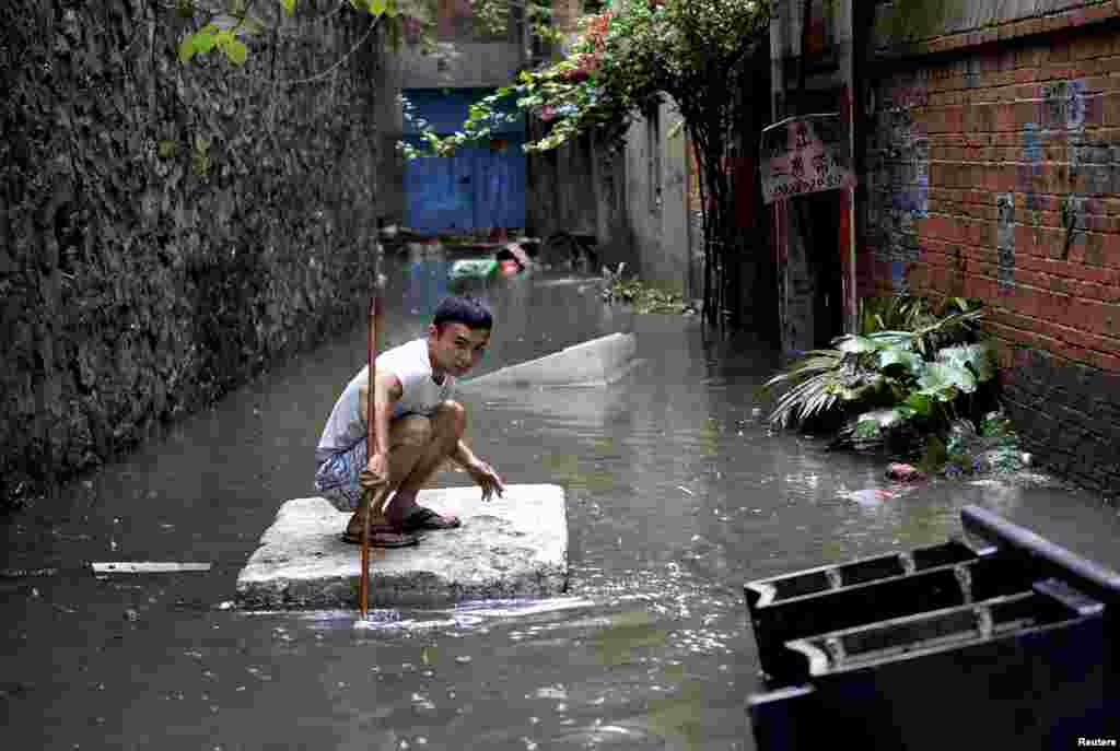 A man travels down a flooded alley on a styrofoam board after heavy rainfall in Liuzhou, Guangxi Zhuang Autonomous Region, China.