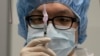 A pharmacist poses with a syringe in a clean room where doses of COVID-19 vaccines will be loaded into syringes, Dec. 9, 2020, at Mount Sinai Queens hospital in New York.