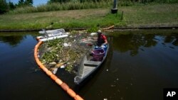 Jack Bates, de la Osprey Initiative, recoge en un río de Nueva Orleáns basura atrapada por la firma Litter Gitter, una de numerosas iniciativas que tratan de evitar que los desechos plásticos lleguen a los océanos. Foto del 27 de mayo del 2022. Foto AP.