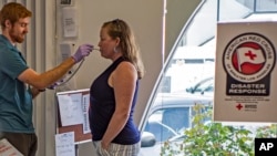 American Red Cross team supervisor Kevin Ashburn, left, screens the body temperature of blood donor Jennifer Love, before her appointment at the American Red Cross office in Santa Monica, Calif., March 26, 2020. 