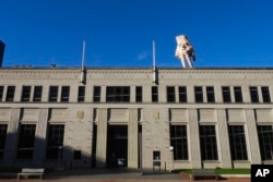 A nearly 5-meter-tall hand sculpture named Quasi is perched on its fingertips atop the roof of an art gallery in Wellington, New Zealand, Oct. 30, 2024.