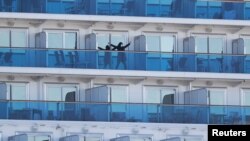 FILE PHOTO: A passenger stretches on the balcony of a cabin of the cruise ship Diamond Princess, where dozens of passengers were tested positive for coronavirus, at Daikoku Pier Cruise Terminal in Yokohama, south of Tokyo, Japan, February 11, 2020.