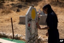 In this Sept. 13, 2019 photo, Layla Taloo visits the grave of a Yazidi woman who took her own life after she was captured by Islamic State militants in Mosul, buried on a hill overlooking the Lalish shrine in northern Iraq.
