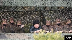 This picture taken on March 12, 2020 and released by North Korea's official Korean Central News Agency (KCNA) shows North Korean leader Kim Jong Un (C) attending a drill by the military's artillery squads.