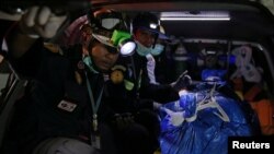 Thai rescue workers sit next to a body on a stretcher, a victim of a boat accident off the tourist island of Phuket, July 7, 2018.