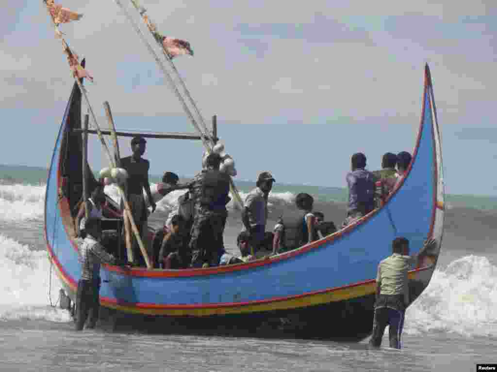 Members of Bangladesh Navy are seen with people rescued from a sunken boat in Bay of Bengal in Teknaf November 7, 2012. A boat carrying about 110 Bangladeshis and Rohingya Muslims from neighbouring Myanmar sank in the Bay of Bengal on Wednesday as they we