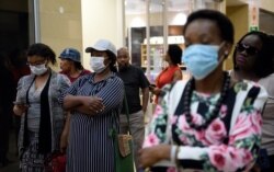 FILE - Customers wearing masks queue at a supermarket in Gaborone, Botswana, March 31, 2020.