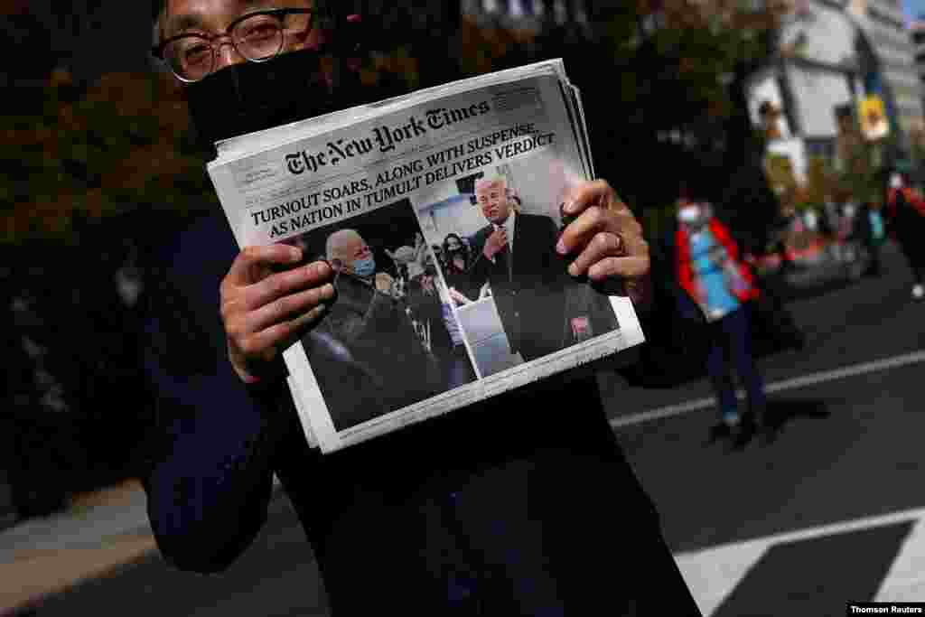 미국 대통령 선거 개표 지연으로 다음 날까지 승자가 확정되지 않은 가운데 워싱턴에서 한 남성이 두 후보의 사진이 1면에 실린 뉴욕타임스 신문을 들고 있다. 