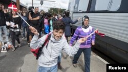 Agitant des drapelets danois, un jeune homme débarque d'un train, avec d'autres migrants, principalement de la Syrie, à la station de Padborg,10 septembre 2015.