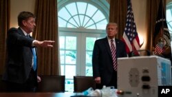 Associate director of the NASA jet propulsion laboratory Dave Gallagher shows President Donald Trump a ventilator created by their engineers during a demonstration in the Cabinet Room of the White House, April 24, 2020, in Washington. 