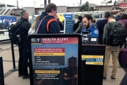 FILE - A health alert for people traveling to China is shown at a TSA security checkpoint at the Denver International Airport in Denver, Colorado, March 2, 2020.
