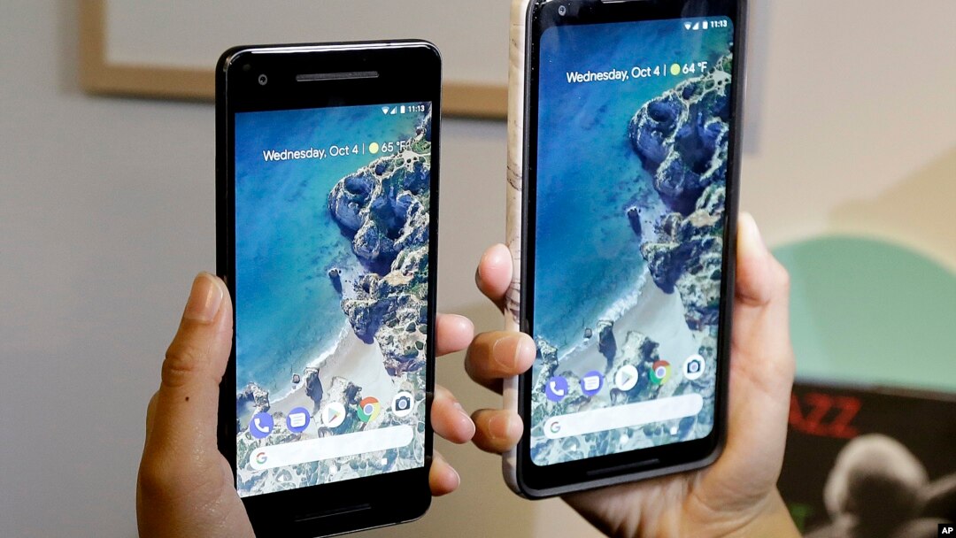 FILE - A woman holds up the Google Pixel 2 phone (L) next to the Pixel 2 XL phone at a Google event at the SFJAZZ Center in San Francisco, Oct. 4, 2017. 