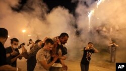 FILE - Protesters carry a man wounded during clashes with police after the presidential election in Minsk, Belarus, Aug. 10. Hundreds of people released from custody after a violent crackdown on protests in Belarus are sharing their accounts of abuse.