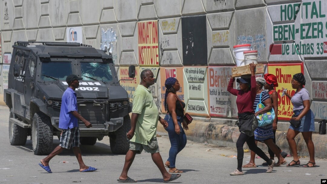 Los peatones pasan junto a un vehículo policial blindado en Puerto Príncipe, Haití, el viernes 4 de octubre de 2024.