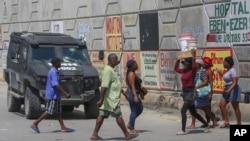 Los peatones pasan junto a un vehículo policial blindado en Puerto Príncipe, Haití, el viernes 4 de octubre de 2024.