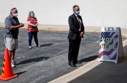 FILE - Oklahoma State Treasurer Randy McDaniel, right, practices social distancing as he waits to take part in early voting for Oklahoma's June 30th primary and special election, at the Oklahoma County Election Board, in Oklahoma City, June 25, 2020.