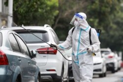 A firefighter wearing protective gear against the spread of COVID-19 coronavirus sprays disinfectant at a residential area in Yangzhou, in China's eastern Jiangsu province, Aug. 11, 2021. (Photo by STR / AFP)