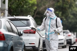 FILE - A firefighter wearing protective gear against the spread of COVID-19 coronavirus sprays disinfectant at a residential area in Yangzhou, in China's eastern Jiangsu province, Aug. 11, 2021. (Photo by STR / AFP)