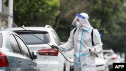 A firefighter wearing protective gear against the spread of COVID-19 coronavirus sprays disinfectant at a residential area in Yangzhou, in China's eastern Jiangsu province, Aug. 11, 2021. (Photo by STR / AFP)