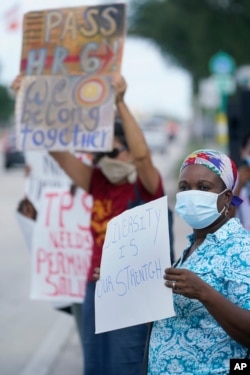 Temporary Protected Status (TPS) holder Kerlyne Paraison, foreground, of Haiti, holds up a sign as she demonstrates during a rally for a permanent solution for TPS holders in front of the Citizenship And Immigration Services Field Office.