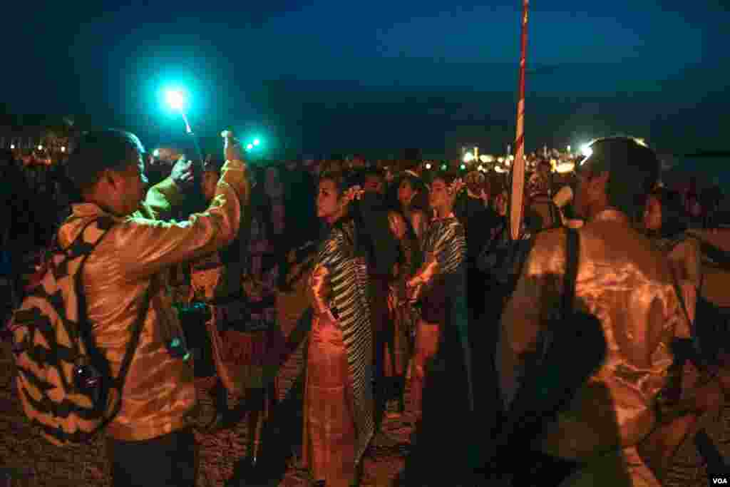 Para wisatawan mengenakan pakaian tradisional menunggu sinar matahari terbit untuk menerangi tempat paling suci Kuil Abu Simbel. Di Kuil Abu Simbel, di Aswan, selatan Mesir, Kamis, 22 Februari 2018. (H. Elrasam/VOA)