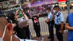 香港警察在维多利亚公园外拦截一名妇女，她身穿纪念六四的T恤，做出反送中运动“五大诉求 缺一不可”的手势。（2021年6月4日）