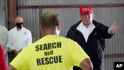 President Donald Trump speaks with first responders as he tours a warehouse being used as a distribution point for relief aid after Hurricane Laura hit the area, Aug. 29, 2020, in Lake Charles, La.