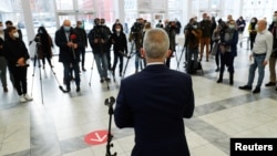 FILE - Members of the media listen as Peter Feldmann, mayor of the city of Frankfurt, speaks during his visit to a vaccination center as the coronavirus outbreak continues in Frankfurt, Germany, Dec. 17, 2020. 