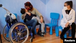 Valentina Perniciaro, wearing a protective mask, holds her son Sirio Persichetti, a 7-year-old with spastic tetraplegia and cerebral palsy who has become an influencer by challenging perceptions of disability. REUTERS/Yara Nardi