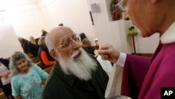 FILE - A priest gives communion host during a mass in a convent of Saint Germain en Laye, west of Paris.