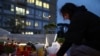 A woman places a candle at the statue of late Pope John Paul II at the Gemelli Hospital, where Pope Francis is being treated for pneumonia, in Rome, March 12, 2025. 